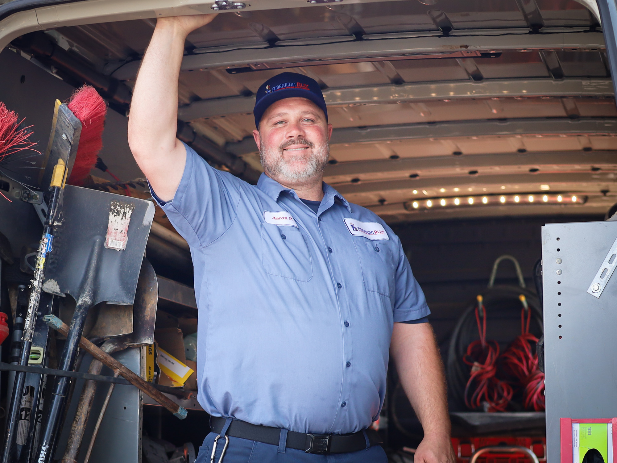 American Ally plumber smiling from inside service van in Ramona, CA.